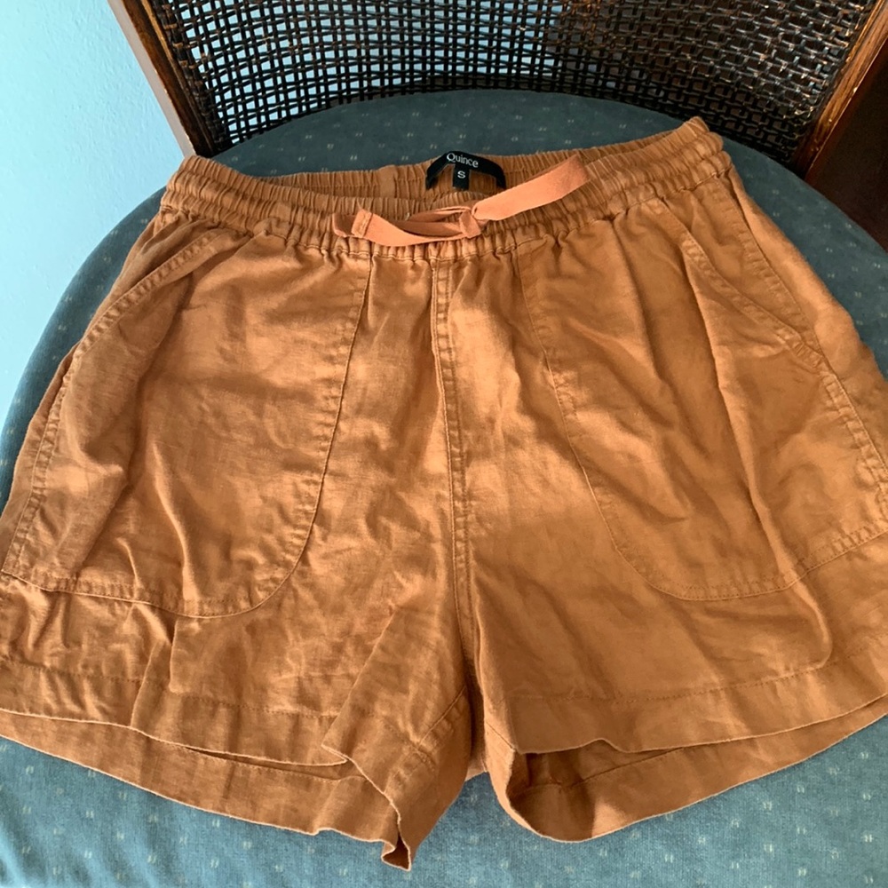 Quince rust colored linen shorts with deep pockets and a tied waist